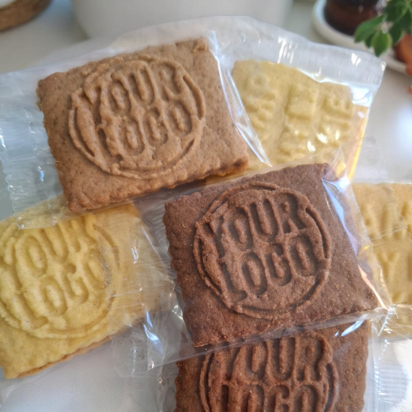Mehrere einzeln verpackte Logokekse in verschiedenen Sorten wie Vanille, Schoko und Karamell – ideal als Messegeschenk, Werbemittel oder Probierpaket