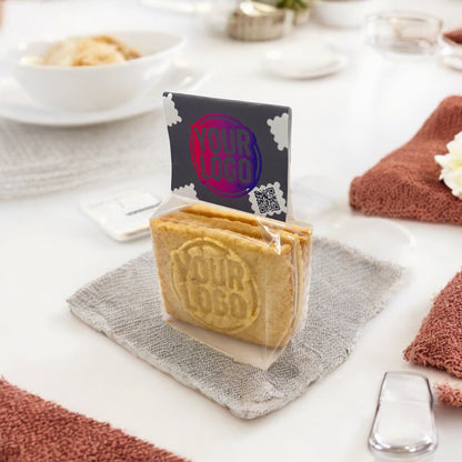 Beutel mit 4 individuell geprägten Logokeksen und Keksreiter, stilvoll platziert auf einem gedeckten Tisch – ideal als Begrüßungsgeschenk im Hotel oder als Tischpräsent bei Veranstaltungen
